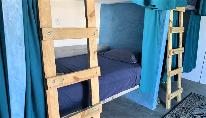 Teal bunk beds at La Ventana Hostel — premium shared sleeping for solo travelers